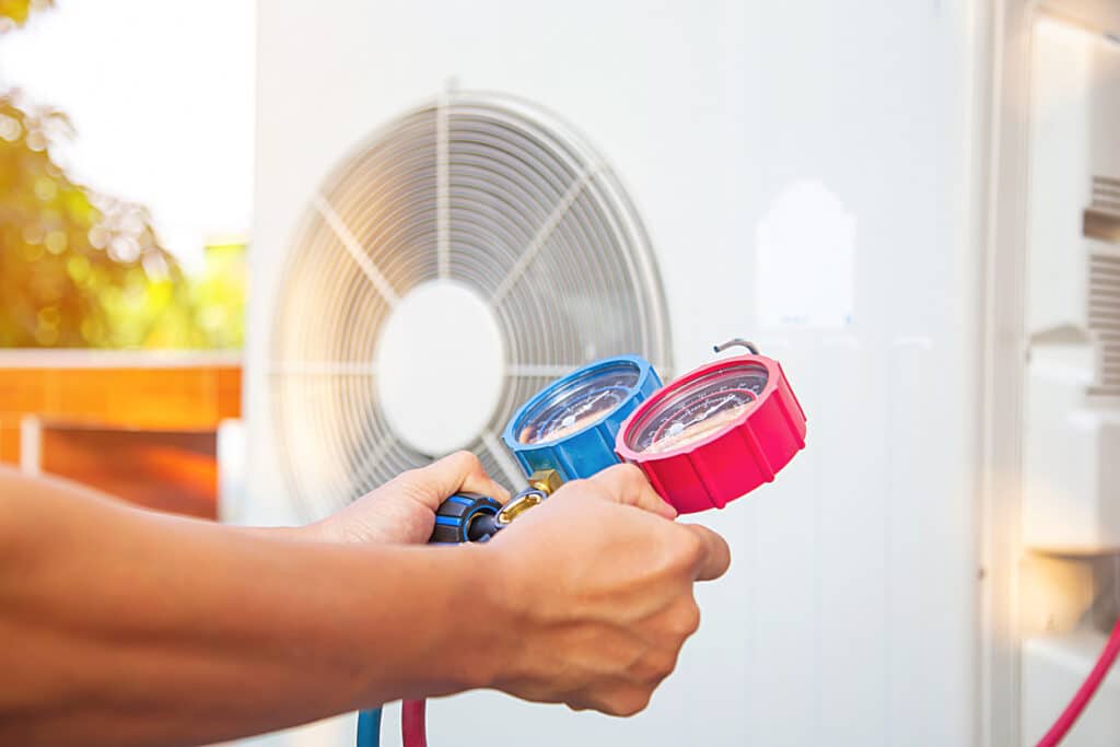 Hands of technician are using a measuring tool to check vacuum pump of air conditioner